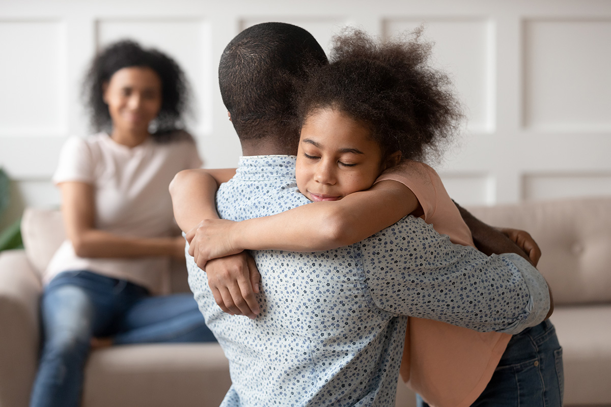 little african-american girl hugging her father with her mom in the background